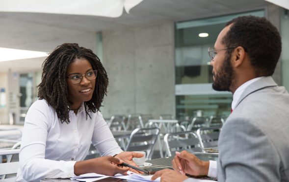 Businesswoman consulting legal experts in coffee shop. Business man and woman meeting in street cafe, talking and smiling. Business discussion concept